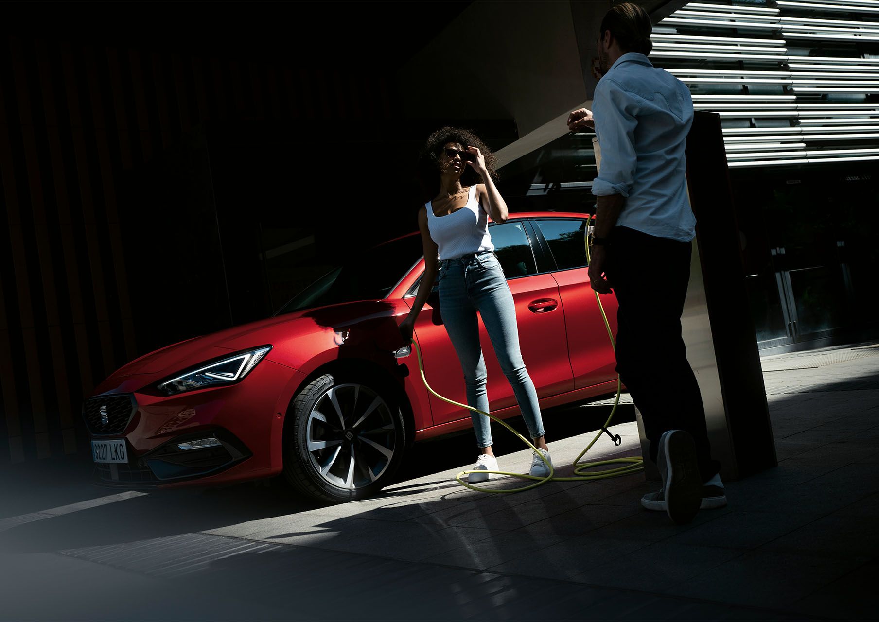 mujer cargando el SEAT León 5 puertas e-hybrid color rojo Desire