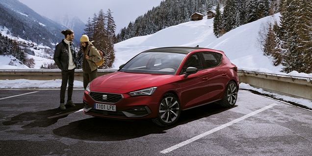 seat león rojo en un entorno invernal de montaña, se enfatiza la sostenibilidad y adaptabilidad para conductores de coches híbridos