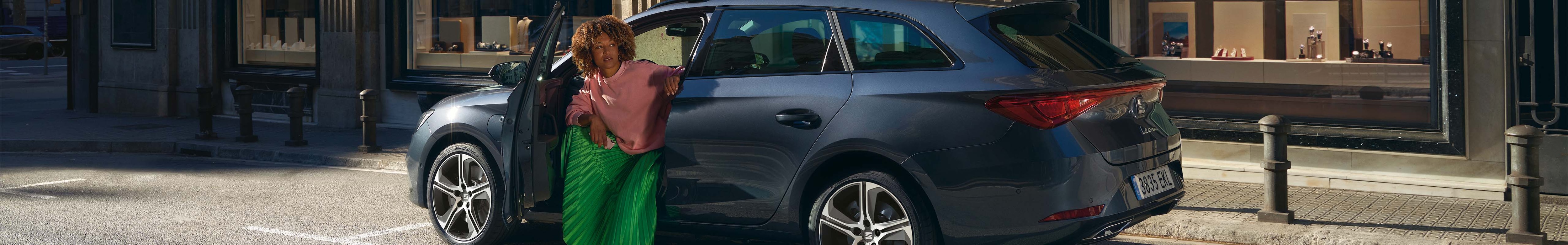 coche híbrido seat sportstourer azul en la Carretera, conductor abriendo la puerta en la ciudad, en sombra