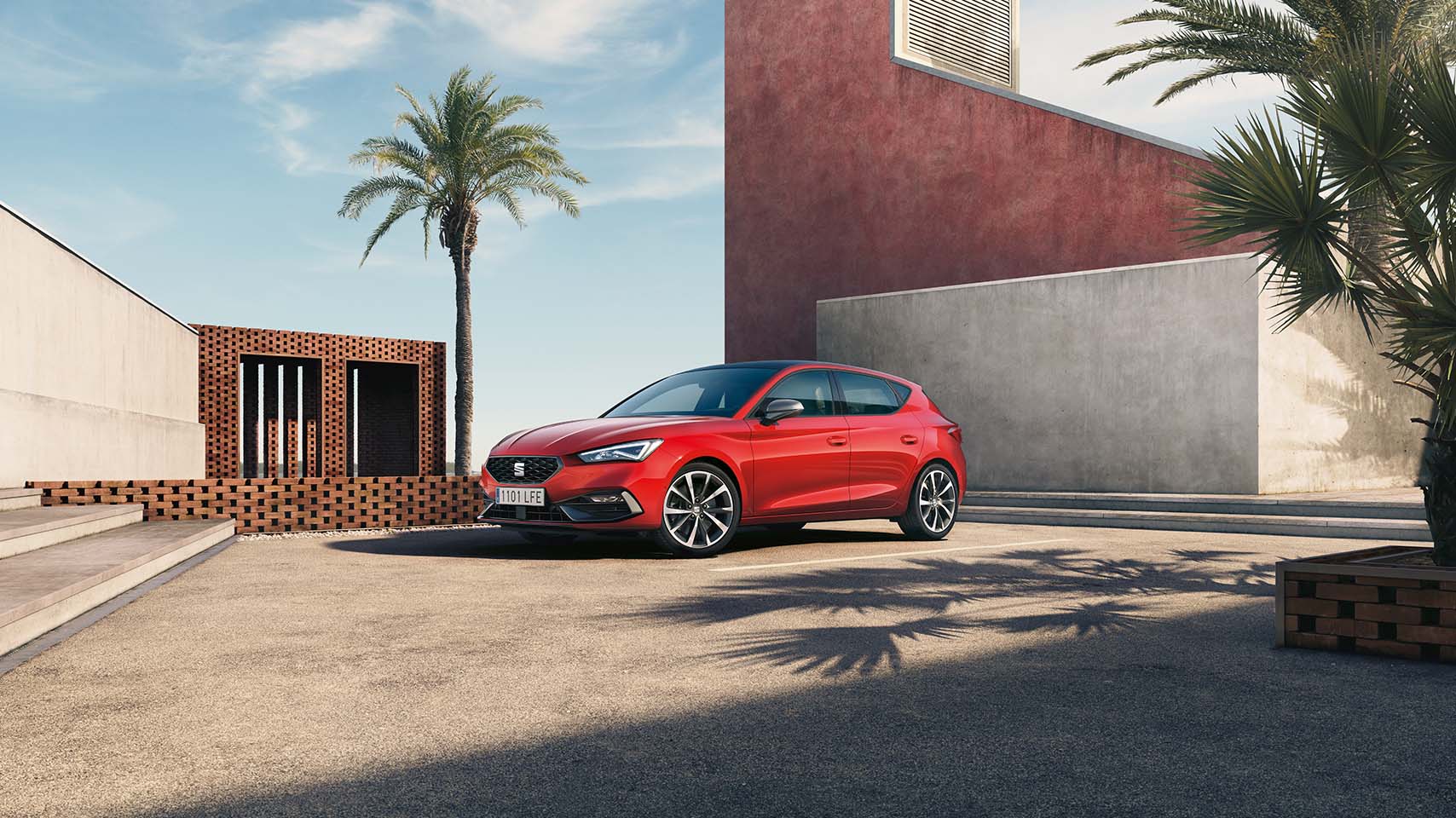 coche micro híbrido, seat leon rojo en aparcamiento público, cielo azul